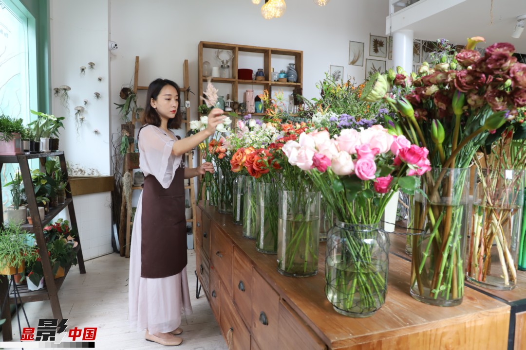 王黎媛是一名河南姑娘，在昆明念完大學(xué)后，就再也舍不下春城的藍(lán)天陽光、青山碧水，更舍不下這里的四時(shí)繁花，于是就干脆留了下來，成了一名媒體人。2017年的時(shí)候又毅然辭去工作，創(chuàng)業(yè)開起了花店，成了都市里的一名“花房姑娘”。圖為王黎媛在自己的花店中整理鮮花。新華網(wǎng) 周亞平/攝 念新洪/文